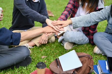 close-up and cropped image, Happy young asian college students sitting in the campus's park, putting...