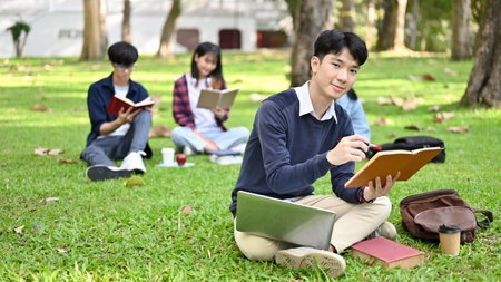 Handsome and smart young Asian male college student doing homework in the campus's park in the afternoon.の写真素材