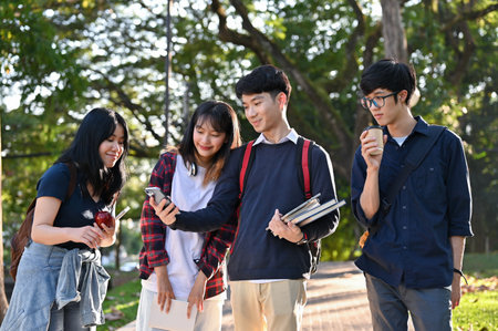 Group of young Asian college students enjoy strolling in the campus's park together after finishing class.の写真素材