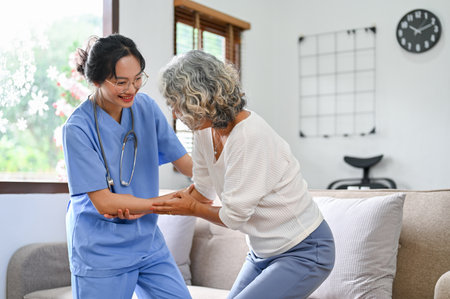 A 60-year-old elderly retire woman being helped by a young female nurse to standup and walk. physical therapy conceptの写真素材