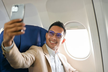 Successful and handsome Asian businessman or CEO taking his picture with smartphone during the...
