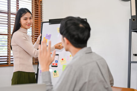 Professional millennial Asian female designer presenting her mobile application's interface...