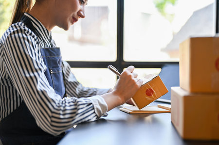 side view, Beautiful and focused millennial Asian female online shop owner preparing shipping...