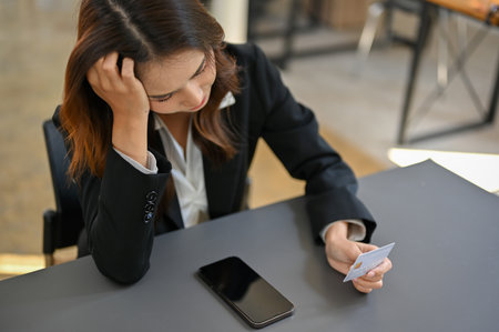 Stressed and unhappy Asian female office employee is having financial problems from using her credit card.の写真素材