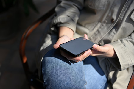 A female using her smartphone while relaxing at the coffee shop on her weekend. cropped and close-up...