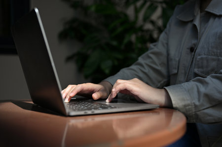 cropped and close-up hand image, A female freelancer using her portable notebook laptop, typing on keyboard, remote working at the cafe.の写真素材
