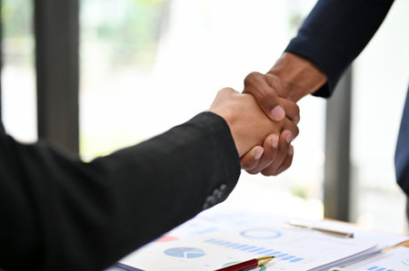 close-up image, Two professional Asian businesspeople shaking hand in the business partnership meeting. teamwork, business contract, success negotiation, business dealing, congratulations, welcomingの写真素材