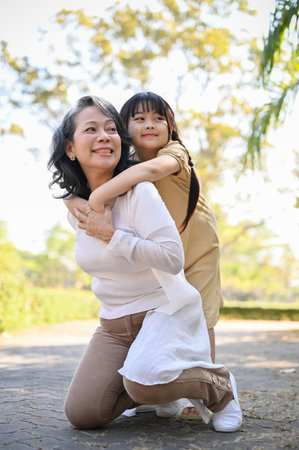 Portrait, Happy and charming Asian grandmother and her lovely granddaughter in the park, piggy back,...