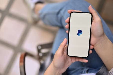 Chiang Mai, Thailand - Feb 6 2023: Top view of a female hands holding a smartphone with PayPal logo on screen, iPhone with PayPal application logo.のeditorial素材