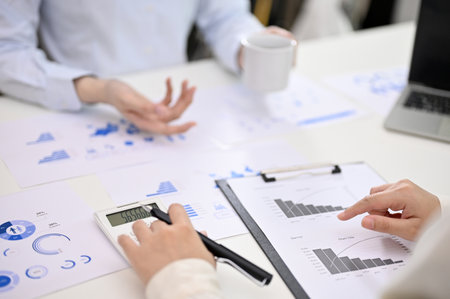 Cropped image of a female accountant using calculator, calculating and analyzing financial data,...