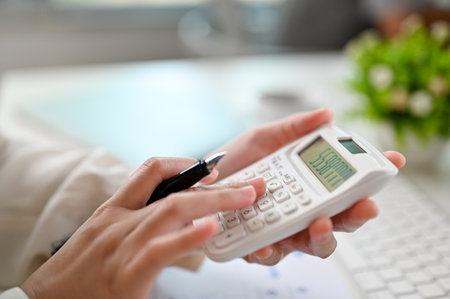 Close-up image of a businesswoman or female accountant using calculator, working on sales and accounts report at her office desk.の写真素材