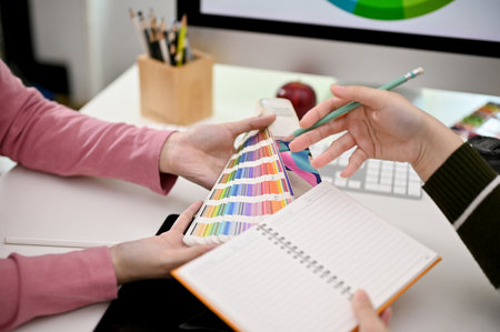 Close-up image of two graphic designers designing their new product together in the office, choosing...