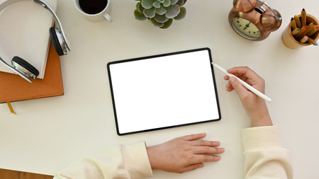 A female using a digital tablet, designing her artwork, working at her minimal white office desk....