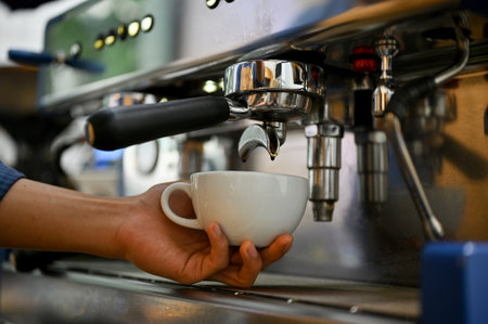 Close-up image of a professional male barista preparing customer's order, making a cup of cappuccino with coffee espresso machine.の写真素材