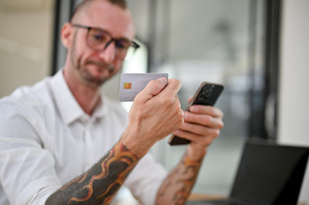 selective focus image, Thoughtful Caucasian man with glasses and tattoo on his arms holding a credit...