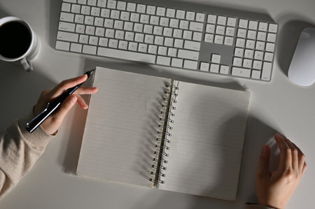 Top view of a female working at her desk, doing homework, writing something on her spiral notebook. blank empty pages.の写真素材