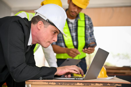 Side view of a determined and professional Caucasian businessman in a white hardhat and business...