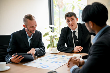 Colleagues meeting in the boardroom, sit at a table together, sharing ideas and discussing project...