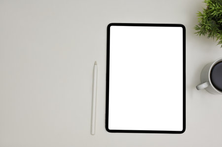 Modern workspace top view with a digital tablet white screen mockup, stylus pen, coffee cup, decor...