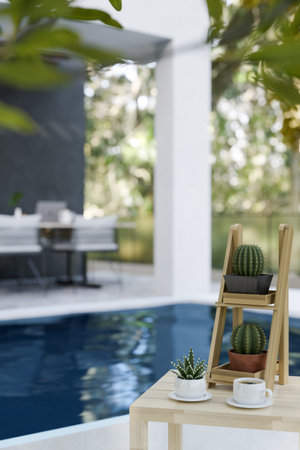 Wood table with cactus shelf and a cup of coffee over blurred background of beautiful home swimming pool. 3d render, 3d illustrationの写真素材