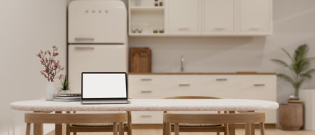 Portable laptop white screen mockup, decor and copy space on white dining table over blurred background of minimal white kitchen with white fridge, sink and cabinet. 3d render, 3d illustrationの写真素材