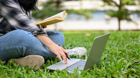 Cropped image of a female college student doing homework, using laptop and researching information...
