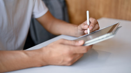 Close up view of young man working in a cafe while using digital tablet. side view. technology...