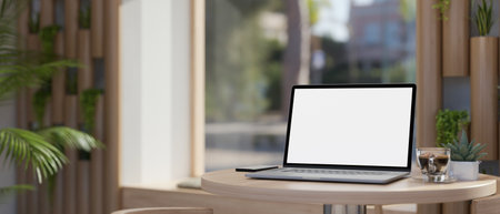 Close-up image of portable laptop white screen mockup, coffee cup and decor plant on minimal wood table in beautiful modern coffee shop or co-working space. 3d render, 3d illustrationの写真素材