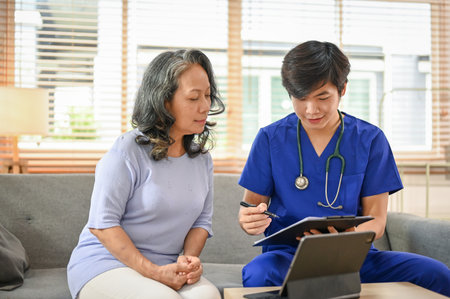 A happy and relaxed 60-year-old retired Asian woman has a medical appointment with a doctor at the hospital.の写真素材
