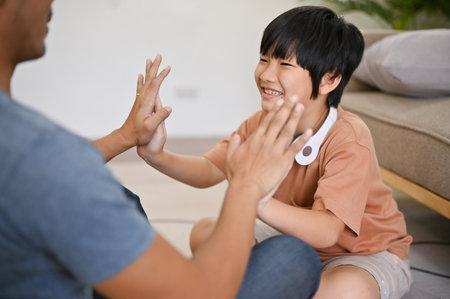Cute and happy Asian little boy playing with his dad, spending fun family games time in the living room together. parenting and childhood conceptの写真素材