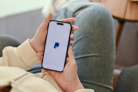 Chiang Mai, Thailand - March 31 2023: A woman using PayPal on her smartphone. iPhone with PayPal logo on screen. close-up imageのeditorial素材