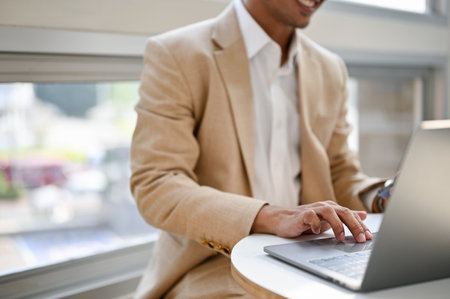 Close-up image of a professional Asian businessman remote working at a cafe, using his laptop.の写真素材