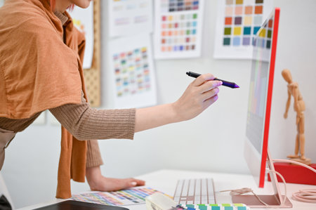 Close-up side view image of a talented female graphic designer working in her studio, pointing stylus pen on computer screen.の写真素材