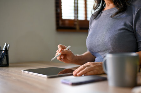Cropped image of an Asian-aged businesswoman using her digital tablet wit stylus pen at her desk.の写真素材