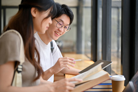 Handsome and smart young Asian male college student tutoring history to his girlfriend at a cafe. teenage love conceptの写真素材