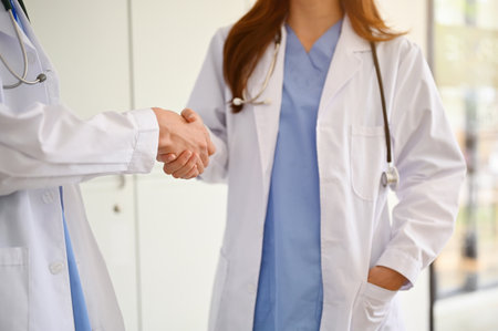 A professional female doctor shakes hands with her colleagues while talking in a hospital corridor. cropped imageの写真素材