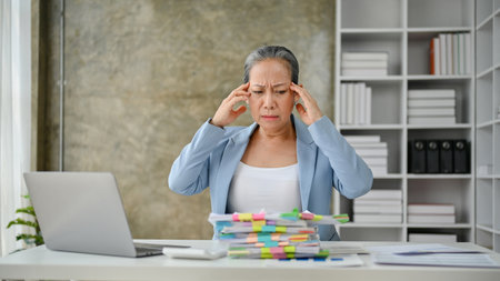 Stressful senior businesswoman feeling upset and tired from the overloaded of the paper work.の写真素材