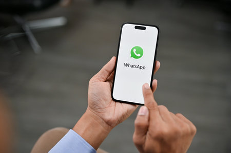 Chiangmai, Thailand - April 27 2023: A man using WhatsApp on his iPhone. WhatsApp logo on iPhone screen mockupのeditorial素材