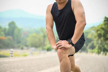 Cropped image, A sporty Asian man in sportswear stretching his legs, getting ready for running in a...
