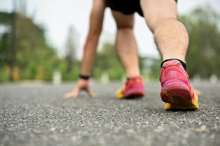 Back view of a man in sportswear is on the road with a starting position, preparing to run....