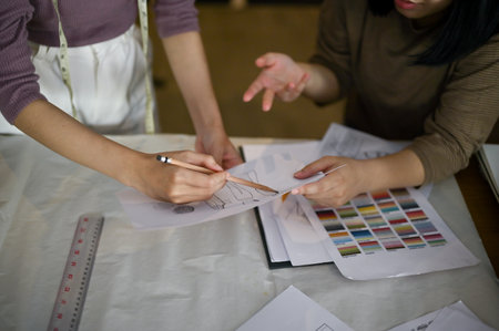 Two professional female fashion designers or dressmakers discussing and checking new model sketches in the studio together. cropped imageの写真素材