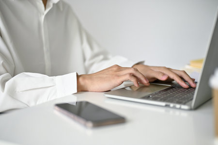 Cropped and close-up image of a businessman typing on laptop keyboard, browsing internet, using...