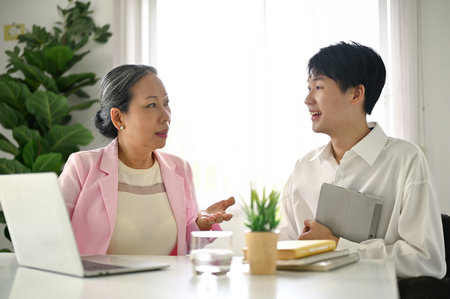 Professional senior Asian female boss is discussing a new project with her marketing project manager in the office.の写真素材