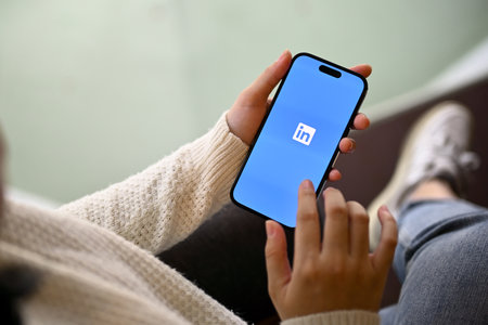 Foto de Chiang Mai, Thailand - May 15 2023: A woman login on LinkedIn application on her smartphone. Close-up image of a woman holding iPhone with LinkedIn logo on screen. - Imagen libre de derechos