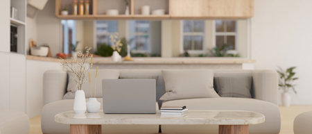 Beautiful minimal bright living room with laptop on a white marble coffee table, comfortable grey sofa, decor and kitchen in the back. 3d render, 3d illustrationの写真素材