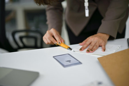Close-up image of a businesswoman or female office worker using a cutter to cut a paper at her desk in the office.の写真素材