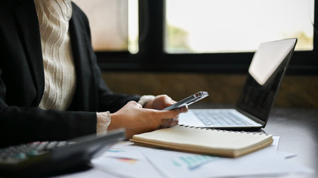 Close-up side view image of a businesswoman using her smartphone at her office desk.