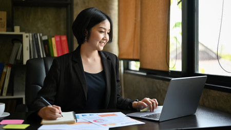 Attractive and professional Asian businesswoman or a female manager in a formal black suit working...