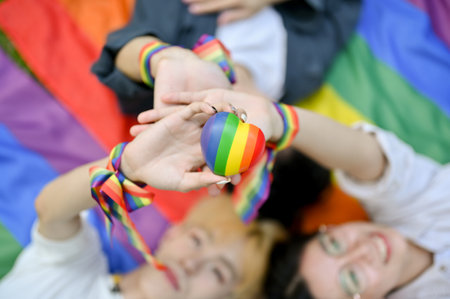 Top view of diverse LGBT friends laying on a pride flag and holding the LGBT heart symbol together. Diversity, Freedom, Equality, LGBTQの写真素材