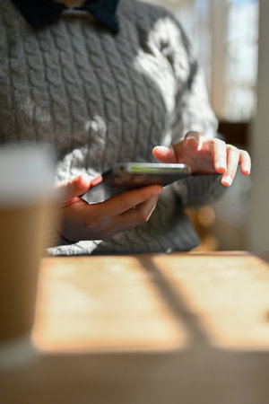 Close-up image of a female using her smartphone at a table in the coffee shop. Lifestyle concept